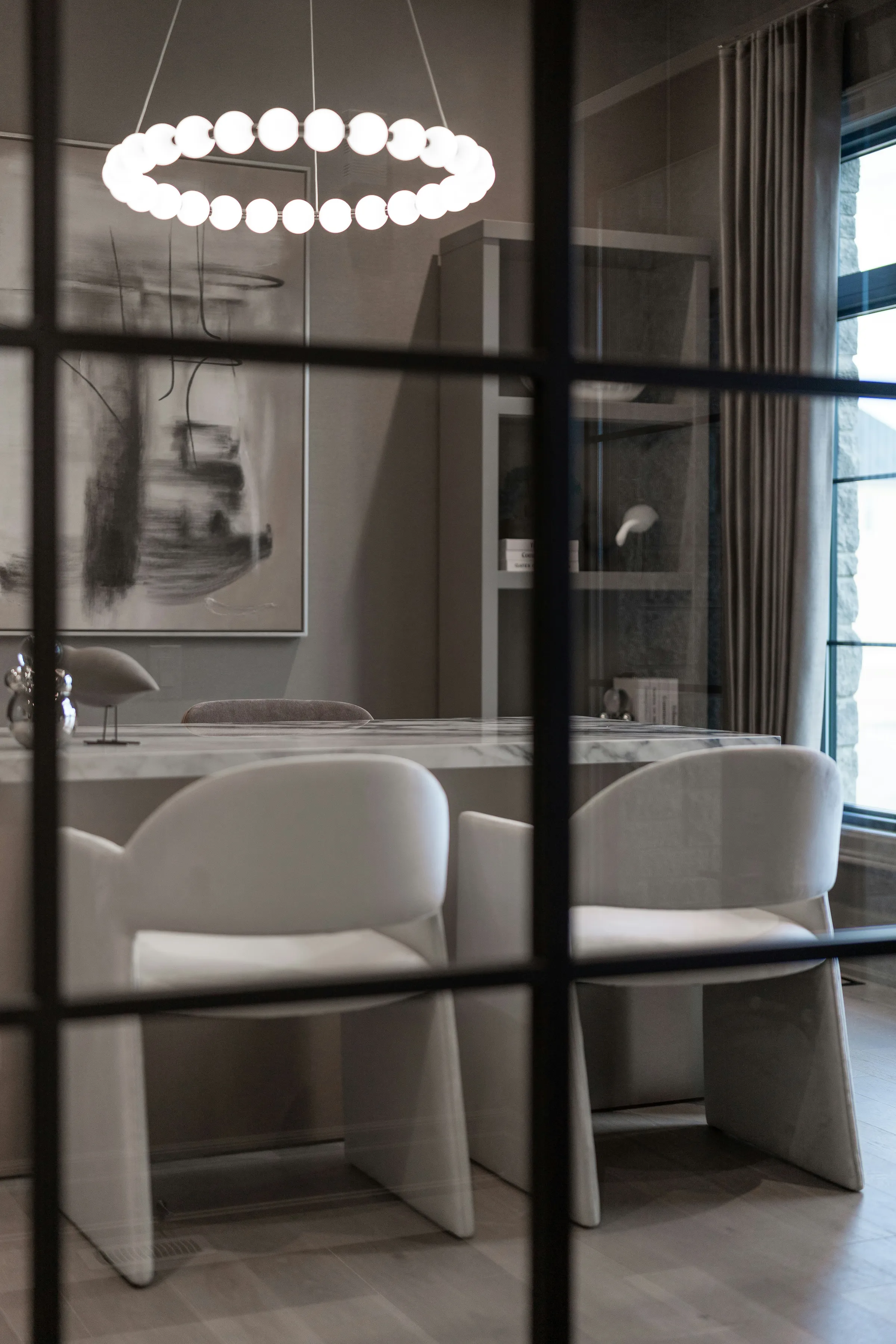 Besprechungsraum mit Marmortisch, hinter einer Sprossen-Glasfront gesehen